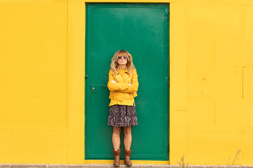 middle aged woman at the green door with yellow wall