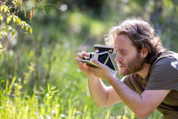 istock Young man taking photos with old polaroid camera, background with copy space 1664136398