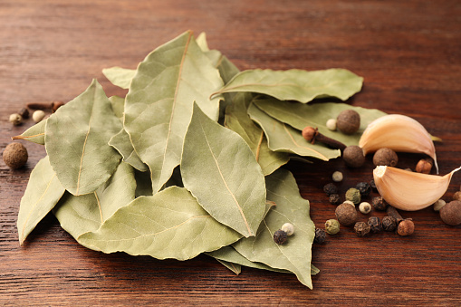 Aromatic bay leaves and spices on wooden table, closeup