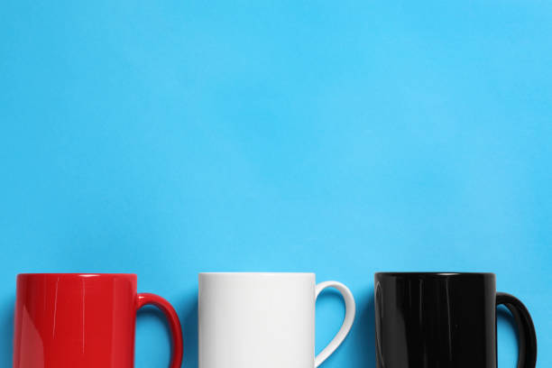 istock Colorful ceramic mugs on light blue background, flat lay. Space for text 1664140248
