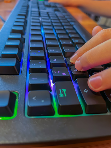 Young Gamer Pressing Keys on Colorful LED Gaming Keyboard During Play