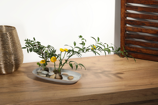 Stylish ikebana with beautiful yellow flowers and green branches carrying cozy atmosphere at home