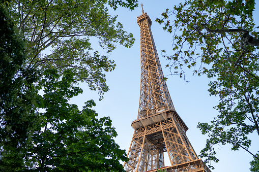 The Eiffel Tower seen through trees with a beautiful summer sky in the background, Paris, France.