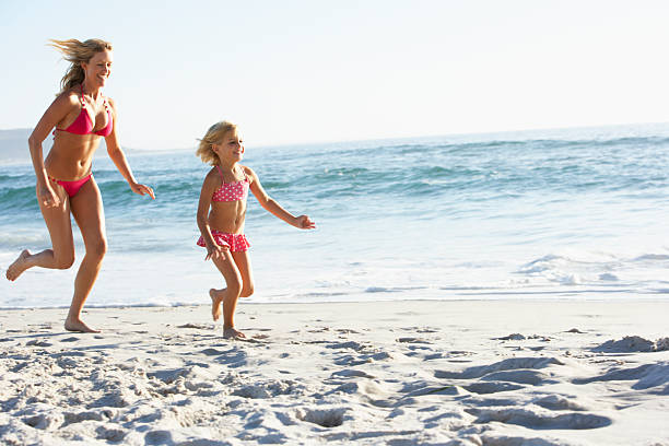 istock Mother And Daughter Running Along Beach 166416710