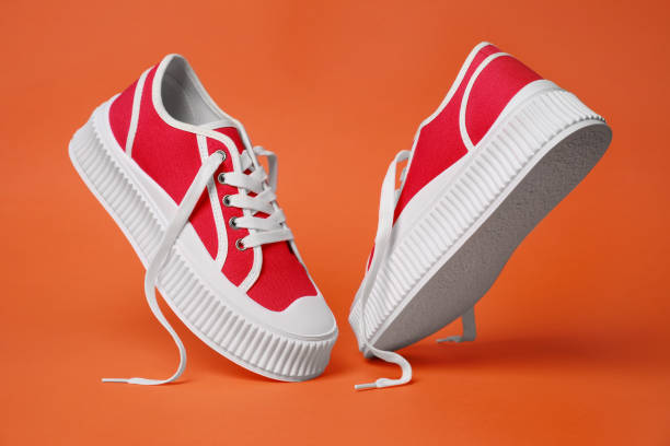 istock Pair of red classic old school sneakers on orange background 1664170192