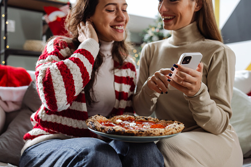 Two young woman ordering pizza on the phone