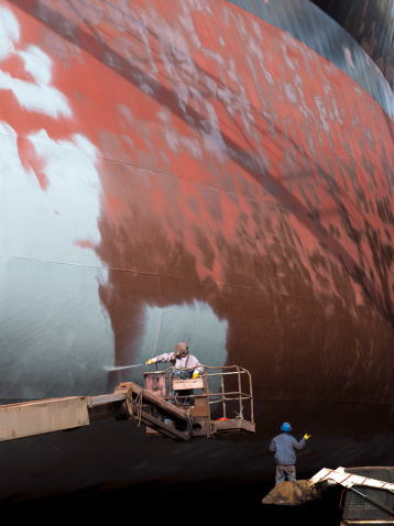 Shipyard workers paintting the ship, unrecognized,