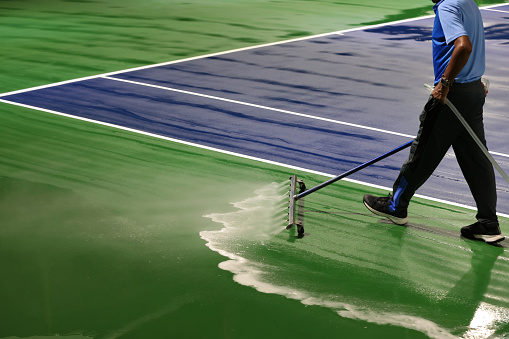 man washing and cleaning the tennis court before the match