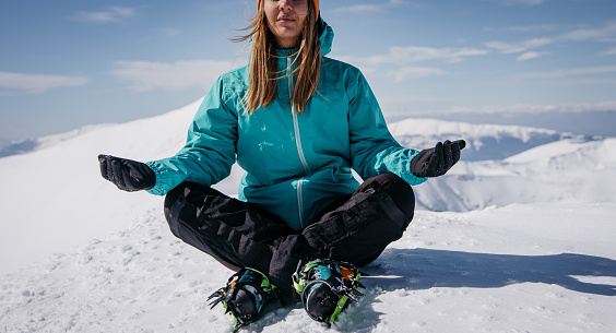 Female climber is meditating the peak of high altitude mountain in winter