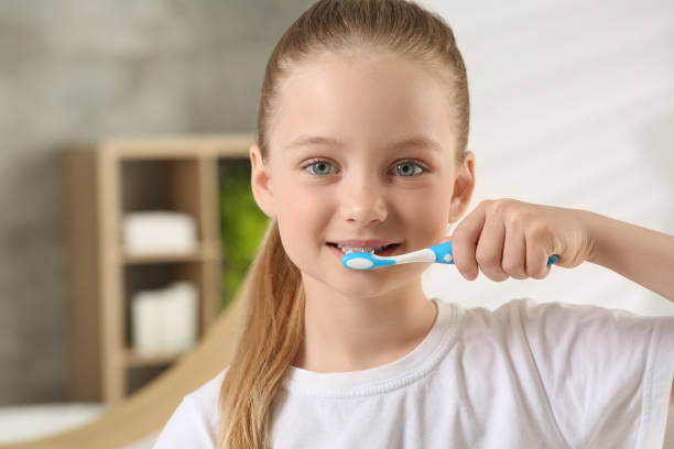 istock Cute little girl brushing her teeth with plastic toothbrush in bathroom, space for text 1664232371