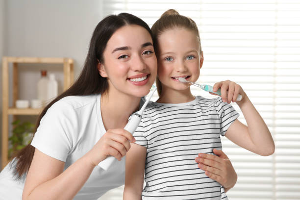istock Mother and her daughter brushing teeth together in bathroom 1664232891