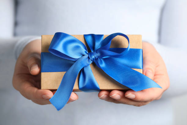 istock Woman holding gift box with blue bow, closeup 1664235993