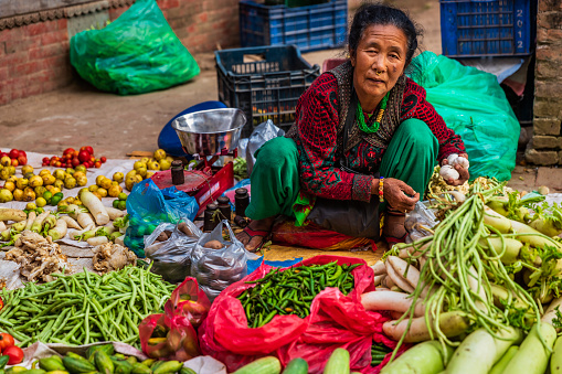 Female Indian street  sellers selling vegetables on the streets of Bhaktapur, Nepal. Bhaktapur is an ancient town in the Kathmandu Valley and is listed as a World Heritage Site by UNESCO for its rich culture, temples, and wood, metal and stone artwork.