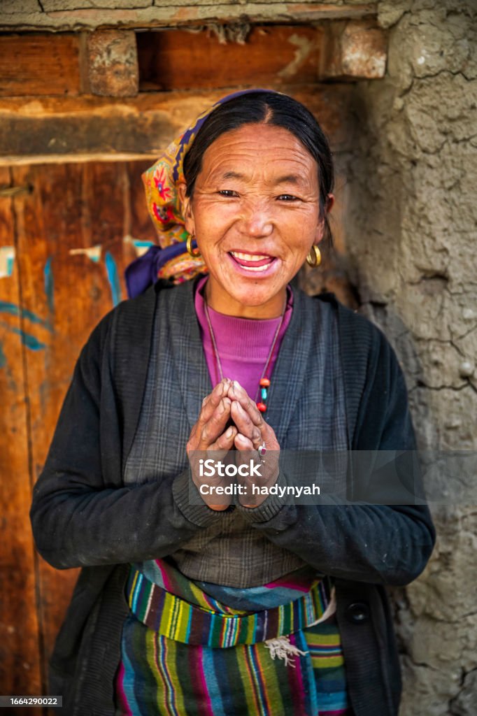 Namaste! Portrait of Tibetan woman, Upper Mustang, Nepal Tibetan woman saying namaste in small village in Upper Mustang. Mustang region is the former Kingdom of Lo and now part of Nepal,  in the north-central part of that country, bordering the People's Republic of China on the Tibetan plateau between the Nepalese provinces of Dolpo and Manang. Tibetan Culture Stock Photo