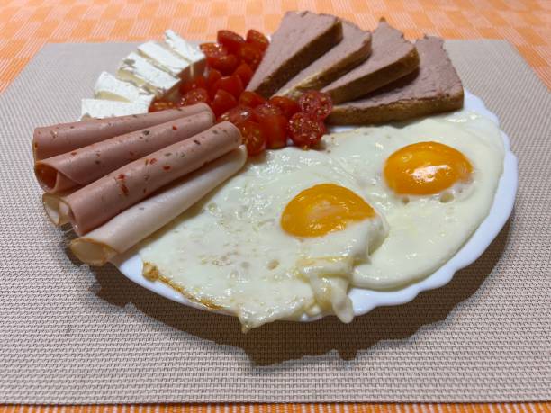 istock Breakfast eggs on a white plate with natural cheese, bread, ham and tomatoes/ top view meal 1664306655