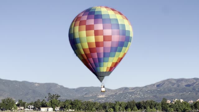 Vivid colored hot air balloon touches lake waters and then rises into early morning sky