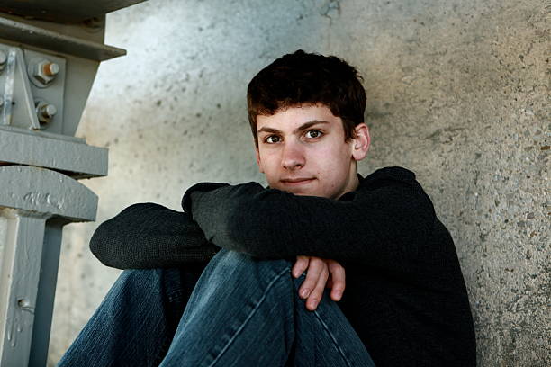 istock Teen Boy Sitting Against Cement Wall 166433717