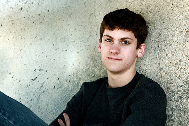 istock Teen Boy Sitting Against Cement Wall 166439024