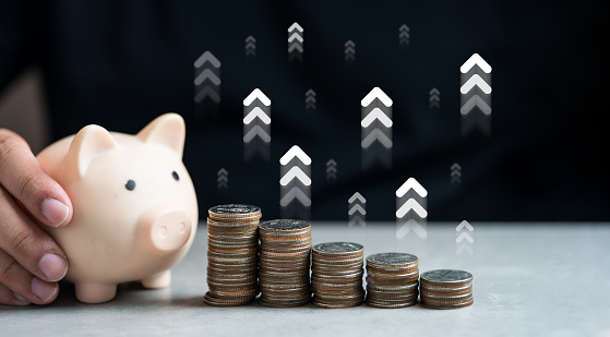 Hand holding piggy bank and stack of coin. Interest rate financial and saving concept. White arrow point up symbol. Investment growth up arrow point