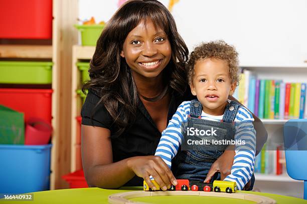 Toddler And Carer Childminder Enjoying Playing A With Train Set Stock Photo - Download Image Now