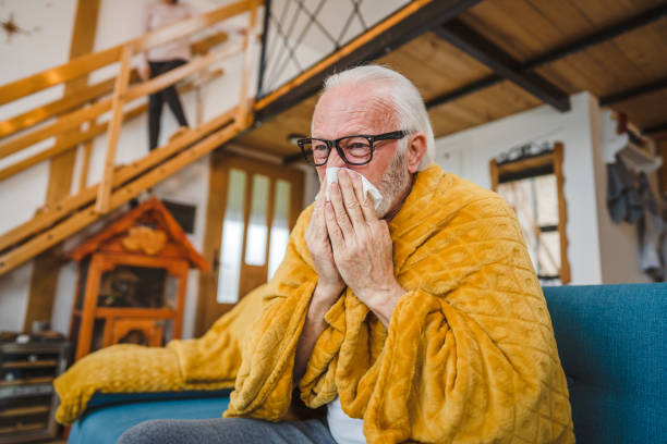 istock one senior man sit on sofa bed hold Paper tissue common cold sneezing 1664413272