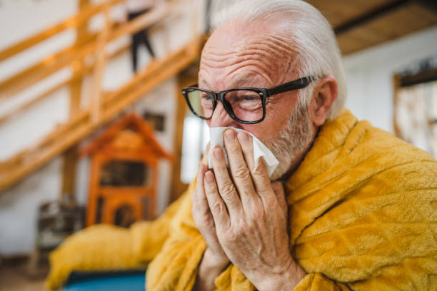 istock one senior man sit on sofa bed hold Paper tissue common cold sneezing 1664413274