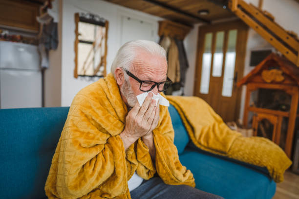 istock one senior man sit on sofa bed hold Paper tissue common cold sneezing 1664413277