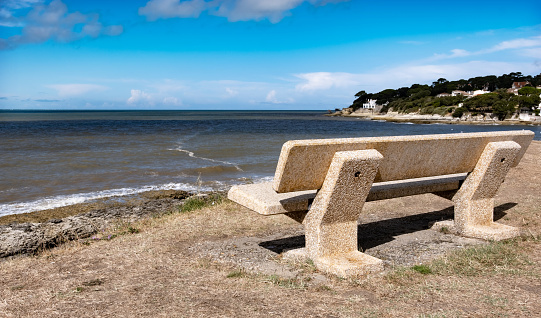 Scenic sea view with bench for resrting and enjoying summer ocean landscape. Seashore and beautiful coastline at sunny day