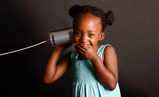 African girl with a tin and string on her ear African girl with a tin and string on her ear string telephone stock pictures, royalty-free photos & images