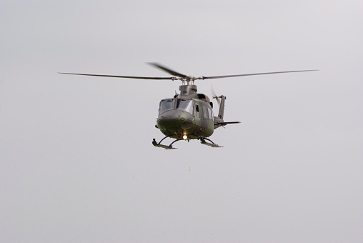 Fort Stockton, TX – November 6, 2020: An MD-500 helicopter is performing a variety of power line utility work and is silhouetted with a worker hanging from the side to perform the work.  The versatile MD-500 is the go to for power line work and it’s ability to be solid working base for utility workers.