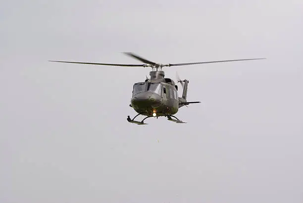 a Huey helicopter in flight against an overcast sky