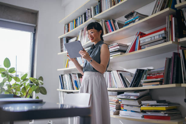 istock A Happy Beautiful Asian Businesswoman With Glasses Using Her Tablet While Working In The Office 1664544450