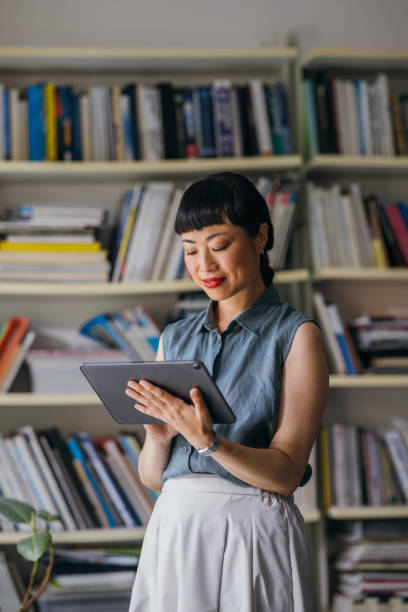 a happy beautiful asian businesswoman working in the office using her tablet - concentration teacher business copy space imagens e fotografias de stock