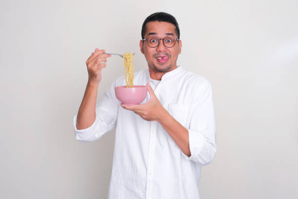 istock Adult Asian man showing funny excited face expression while eating noodle 1664559612
