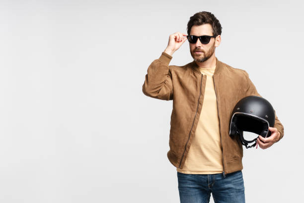 istock Serious bearded man biker holding motorcycle helmet and looking away 1664568124
