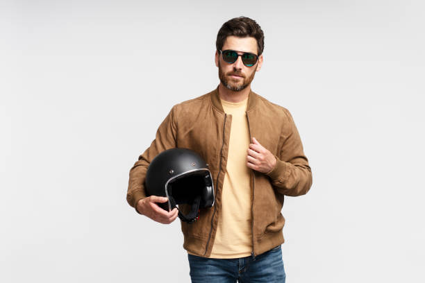 istock Confident serious bearded man biker holding motorcycle helmet and looking at camera 1664568129