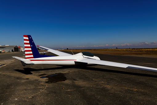 Glider Plane With Red White And Blue Painting Scheme Sitting On Ground At Small Airport Northern California