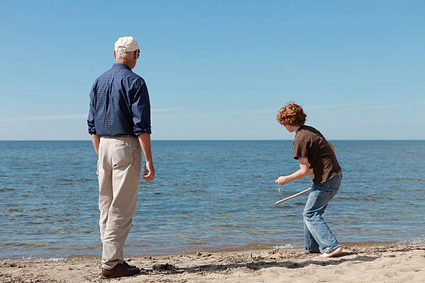 istock Grandfather and Grandson Skipping Stones at Beach 166473782