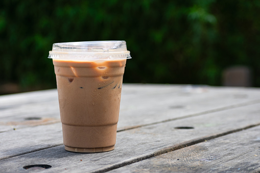 An iced cup of coffee sits in the sunshine in a strawless cup.