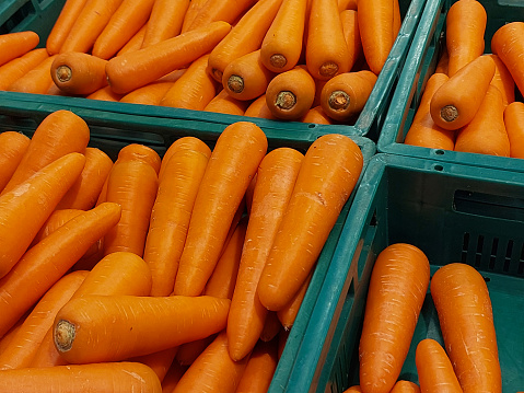 Carrots are arranged in a green basket.  in the department store's fruit and vegetable section, for consumers to select from.