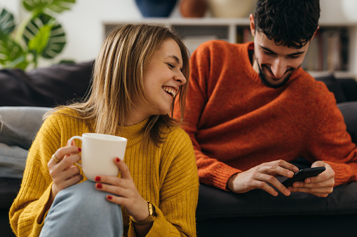 Man and a woman are laughing and looking at the phone