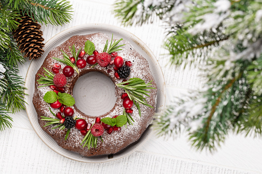 Christmas cake decorated with pomegranate seeds, cranberries and rosemary. Flat lay