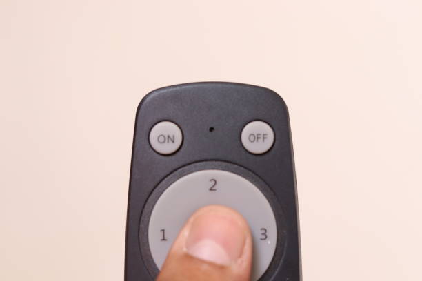 istock A Person Holding Black colour Fan Remote while clicking the centre button in an isolated white background 1664949955