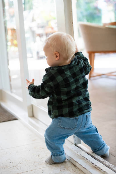 First Steps Young Toddler learning to Walk Young toddler learning to walk and move around the house, interacting with toys. walking into glass door stock pictures, royalty-free photos & images