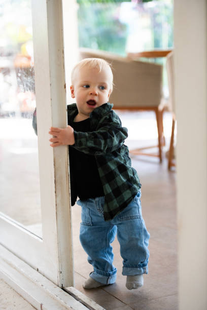 First Steps Young Toddler learning to Walk Young toddler learning to walk and move around the house, interacting with toys. walking into glass door stock pictures, royalty-free photos & images