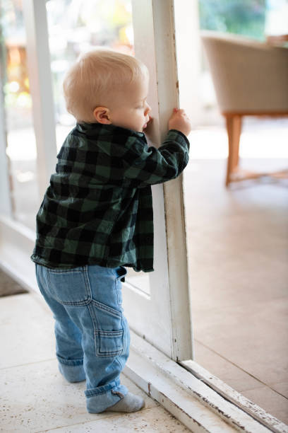 First Steps Young Toddler learning to Walk Young toddler learning to walk and move around the house, interacting with toys. walking into glass door stock pictures, royalty-free photos & images