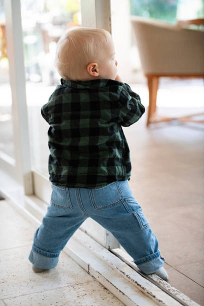 First Steps Young Toddler learning to Walk Young toddler learning to walk and move around the house, interacting with toys. walking into glass door stock pictures, royalty-free photos & images