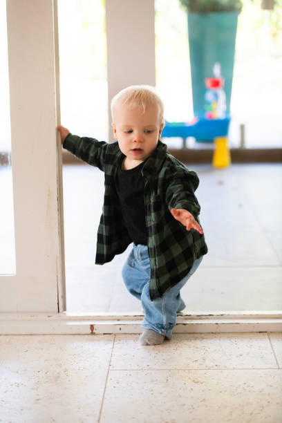 First Steps Young Toddler learning to Walk Young toddler learning to walk and move around the house, interacting with toys. walking into glass door stock pictures, royalty-free photos & images