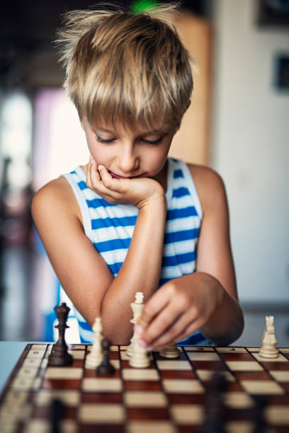 istock Little boy thinking about his move in game of chess 1665047240