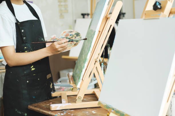 istock Young Asian female artist painting on canvas doing art projects on her studio. 1665082785